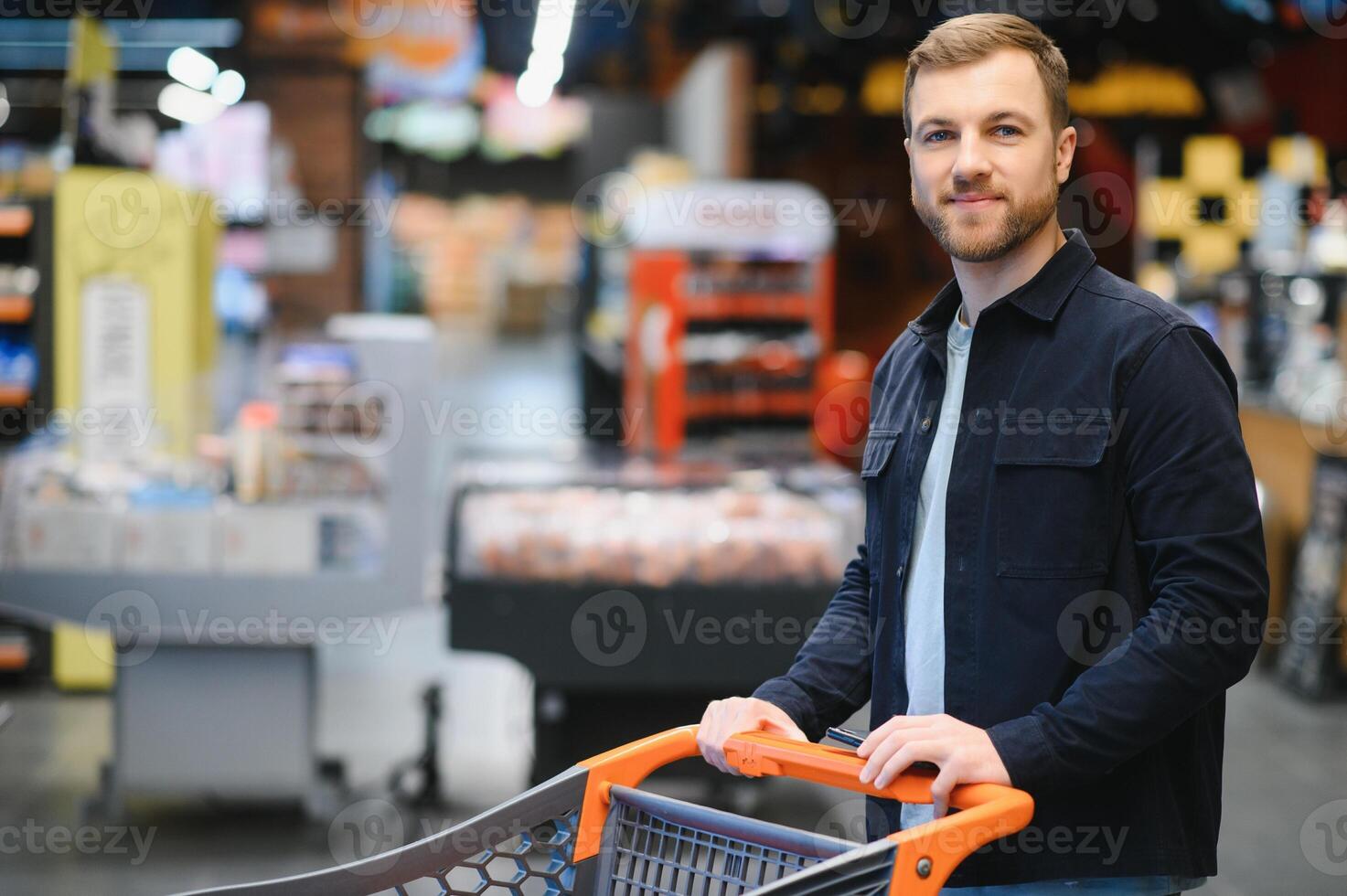 hermoso hombre comprando algunos sano comida y bebida en moderno supermercado o tienda de comestibles almacenar. estilo de vida y consumismo concepto. foto