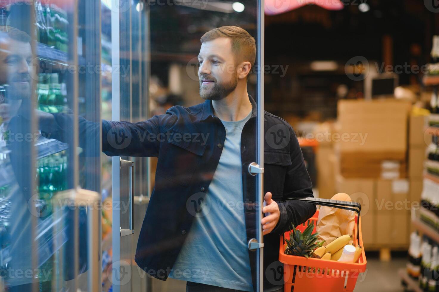 Handsome man buying some healthy food and drink in modern supermarket or grocery store. Lifestyle and consumerism concept. photo