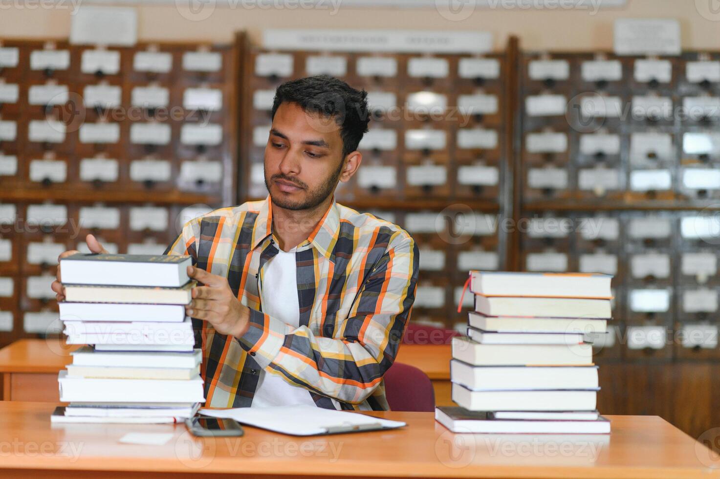 Happy smart indian or arabian guy, mixed race male, university student, in the library photo