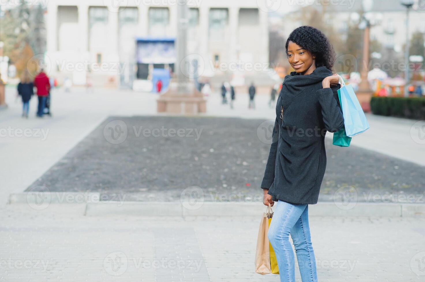 Portrait of beautiful young black woman smiling with shopping bags outside photo