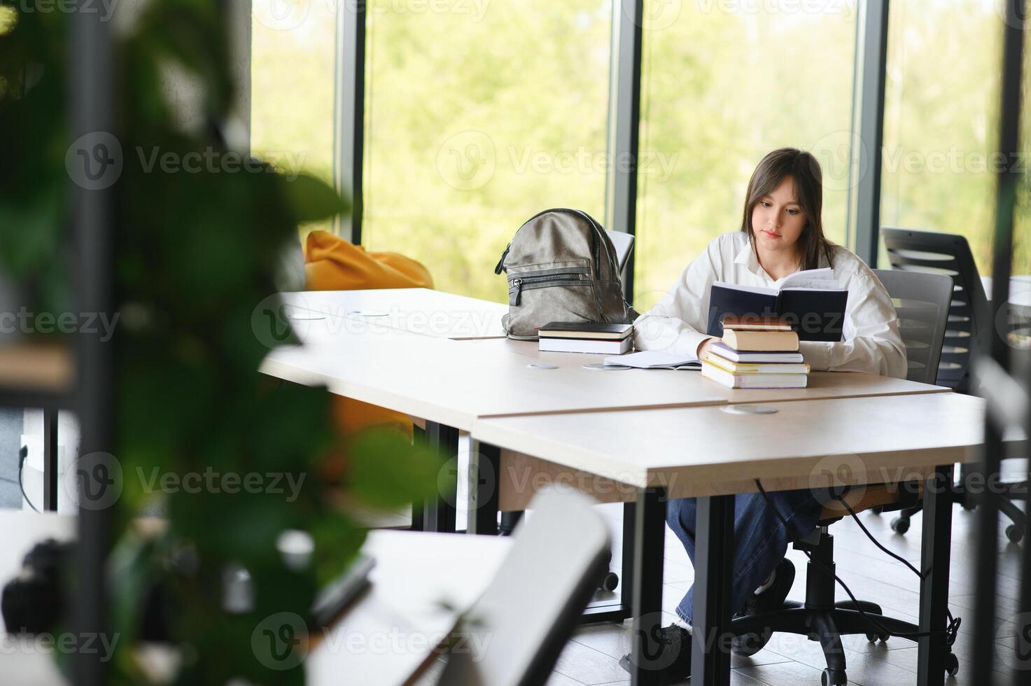 Teen girl studying with textbook writing essay learning in classroom. photo