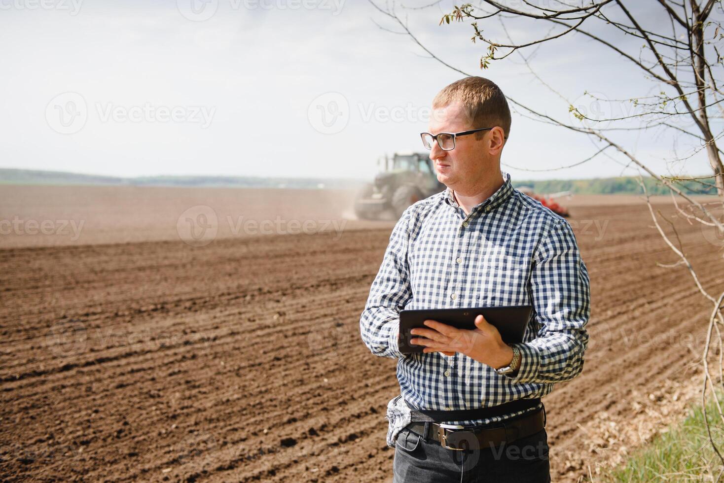 farmer on background of tractor sowing field. Work in the field. Agriculture concept. Farm work in the field in spring photo