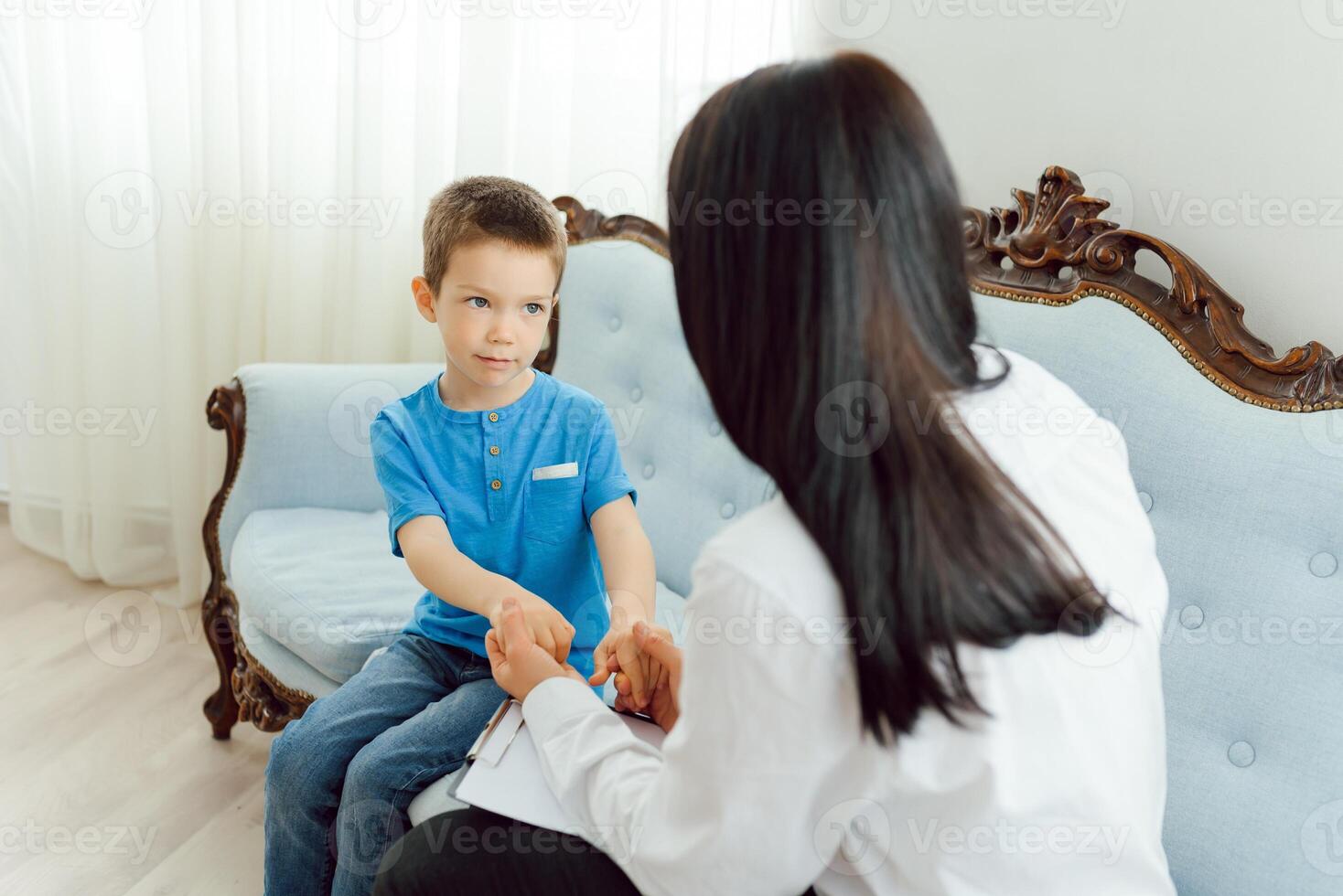 Young female psychologist working with little boy in office photo