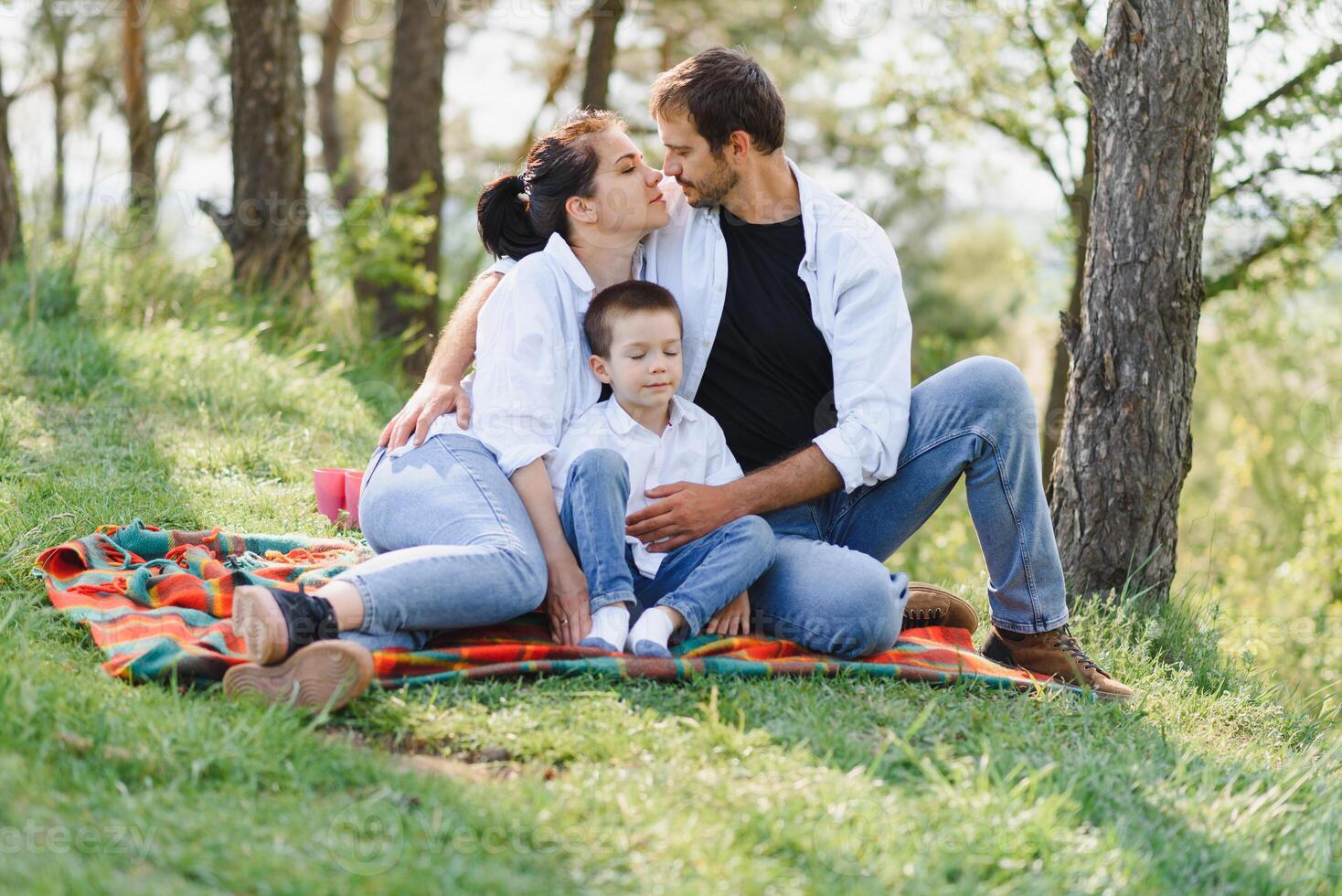 happy young family spending time outdoor on a summer day have fun at beautiful park in nature while sitting on the green grass. Happy family. photo