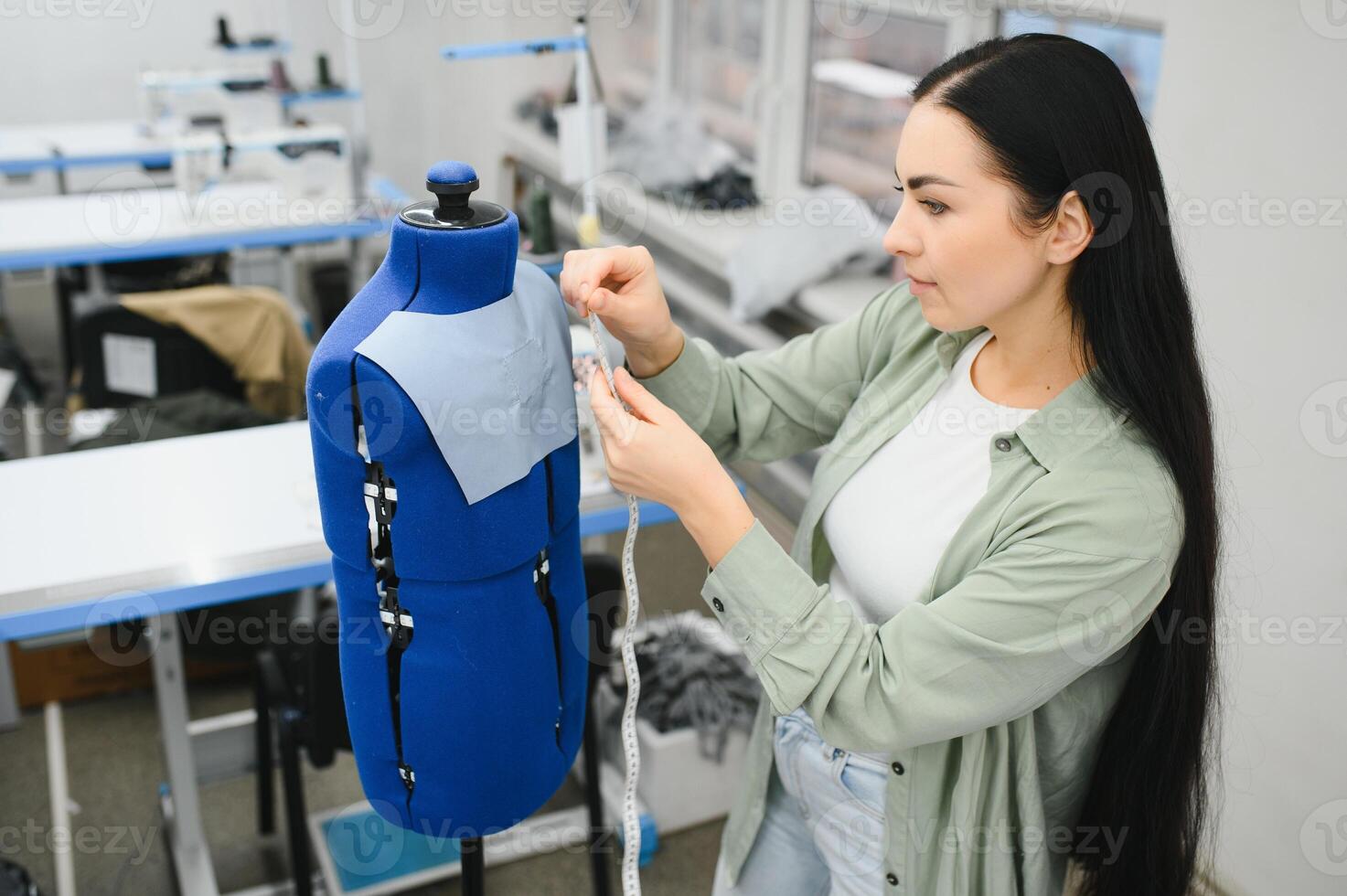 joven modista mujer cose ropa en trabajando mesa. sonriente costurera y su mano cerca arriba en taller. foto