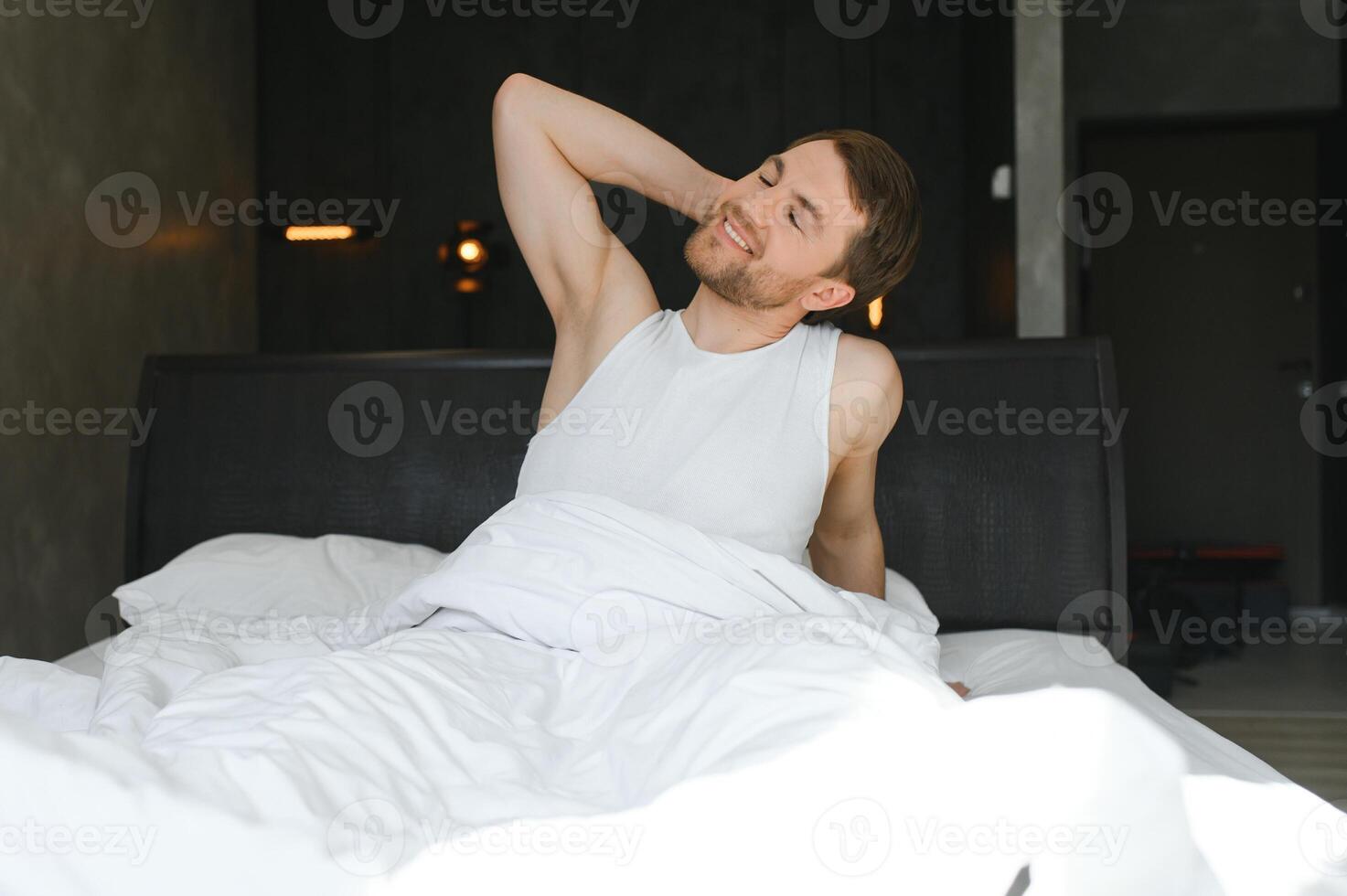 Cheerful Man Waking Up Lying In Cozy Bed At Home On Weekend Morning. Healthy Sleep Concept photo