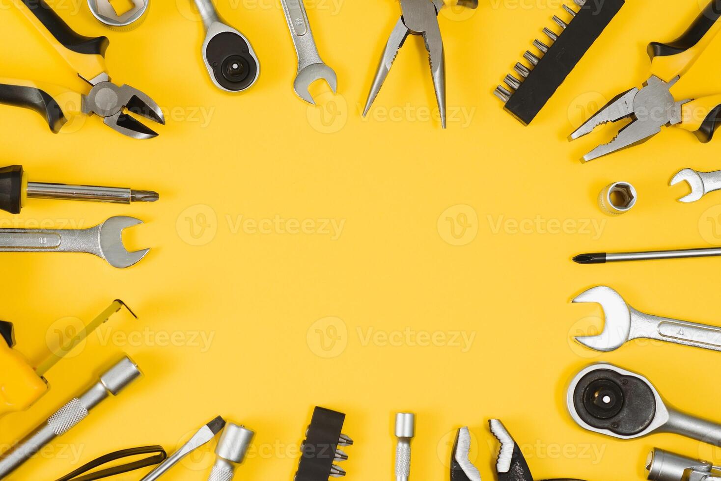 Yellow and black handy tools pilers and screwdriver isolated on yellow background. photo