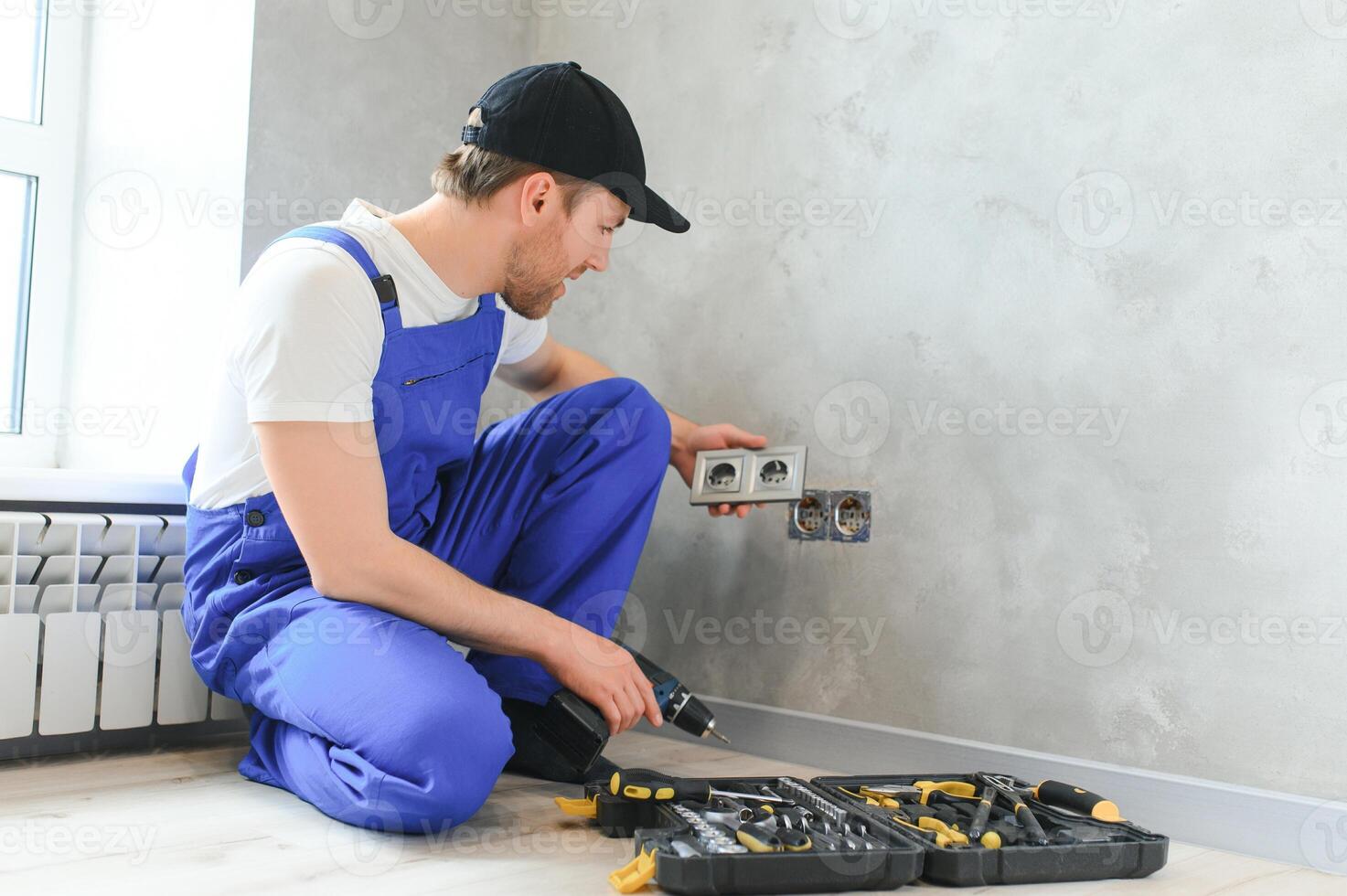 Construction worker electrician assembles an electrical outlet in an apartment photo