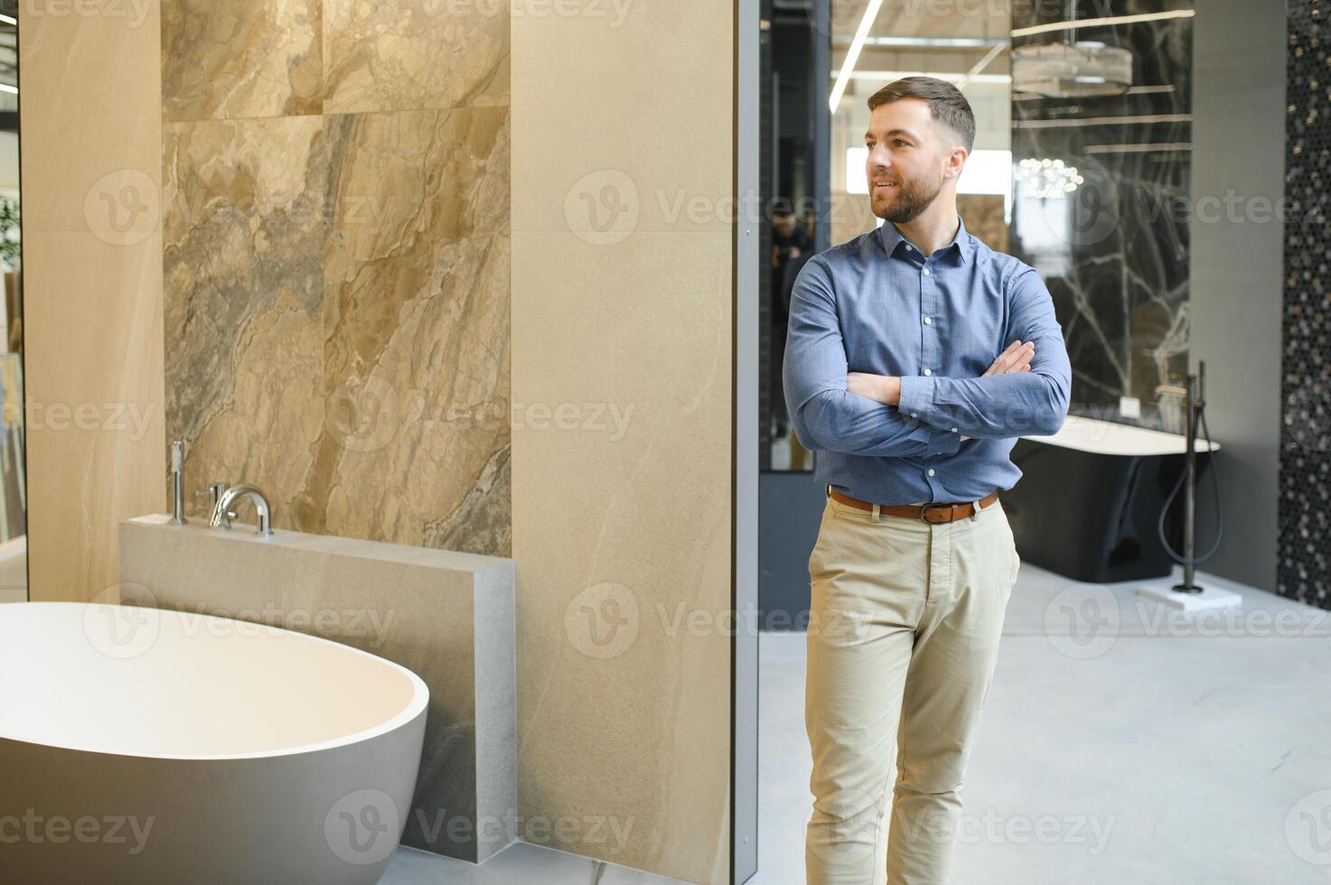 Portrait of buyer in bathroom store. Man is choosing bathtub for his apartment photo
