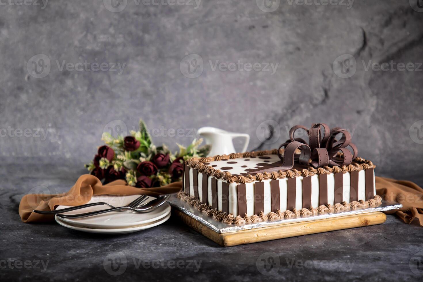 Square Chocolate Cake with rose flowers, spoon and fork served on board isolated on napkin side view of cafe baked food photo
