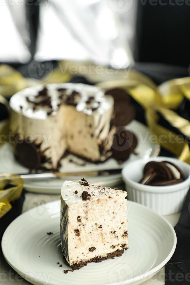 Oreo Cheesecake slice include chocolate, cream, sugar with fork and flowers served in plate isolated on napkin side view of cafe food photo