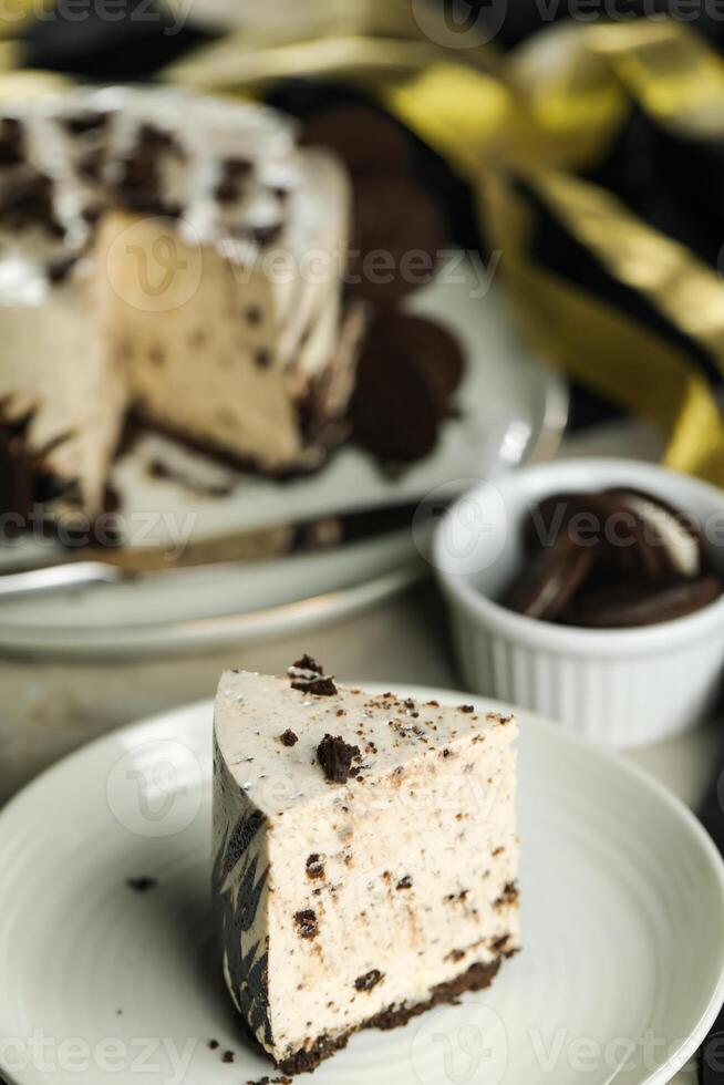 Oreo Cheesecake slice include chocolate, cream, sugar with fork and flowers served in plate isolated on napkin side view of cafe food photo