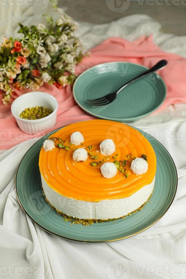 Mango Yogurt Cake topping with pistachio fork and flowers served in plate isolated on napkin side view cafe bake food photo