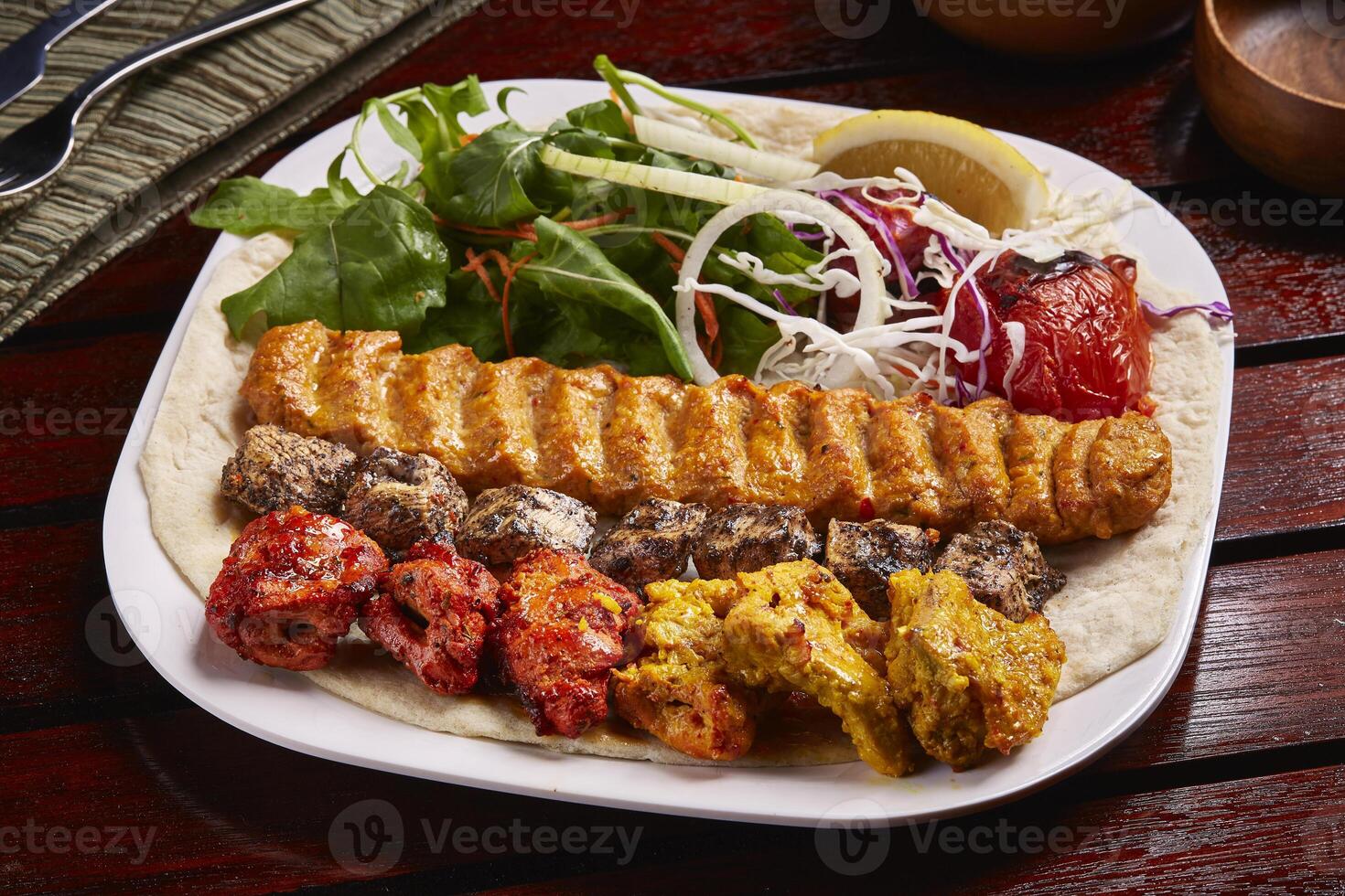 Chicken Mixed Grills platter with salad, lemon, bread served in dish isolated on table side view of middle east food photo