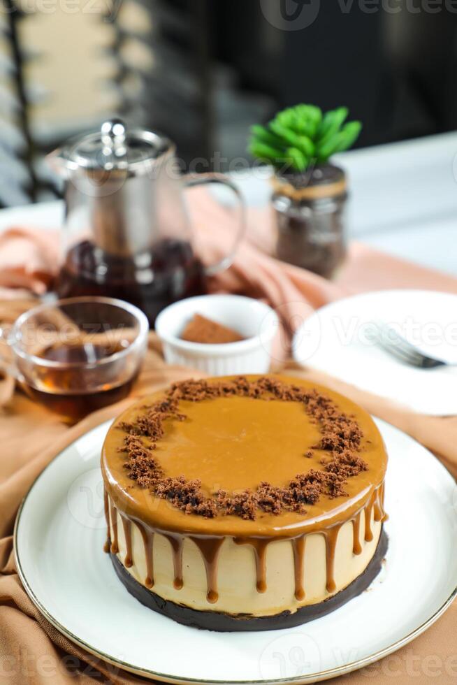Salted Caramel Blondie cake include chocolate cream, sugar with fork, cup of coffee and pot served on board isolated on napkin side view of cafe food photo