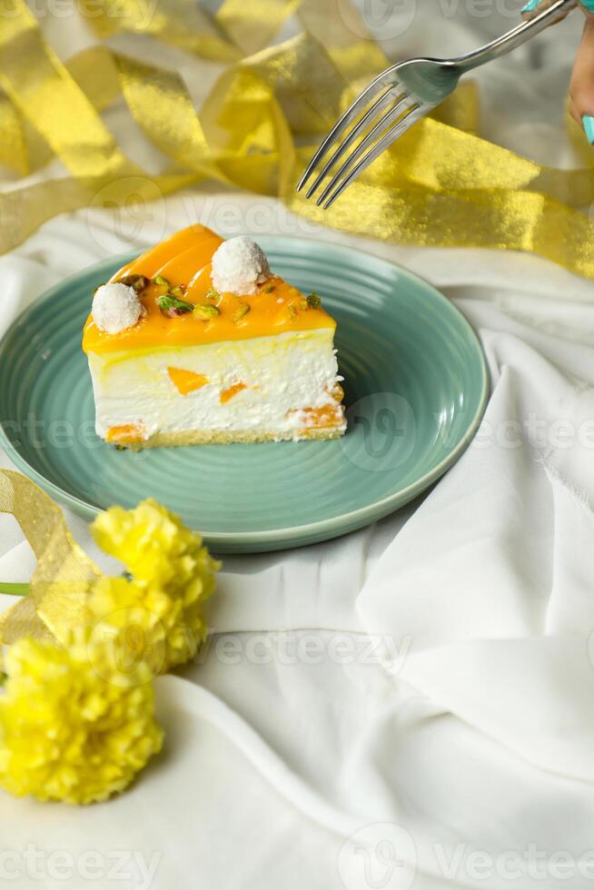 Mango Yogurt Cake slice topping with pistachio fork and flowers served in plate isolated on napkin side view cafe bake food photo