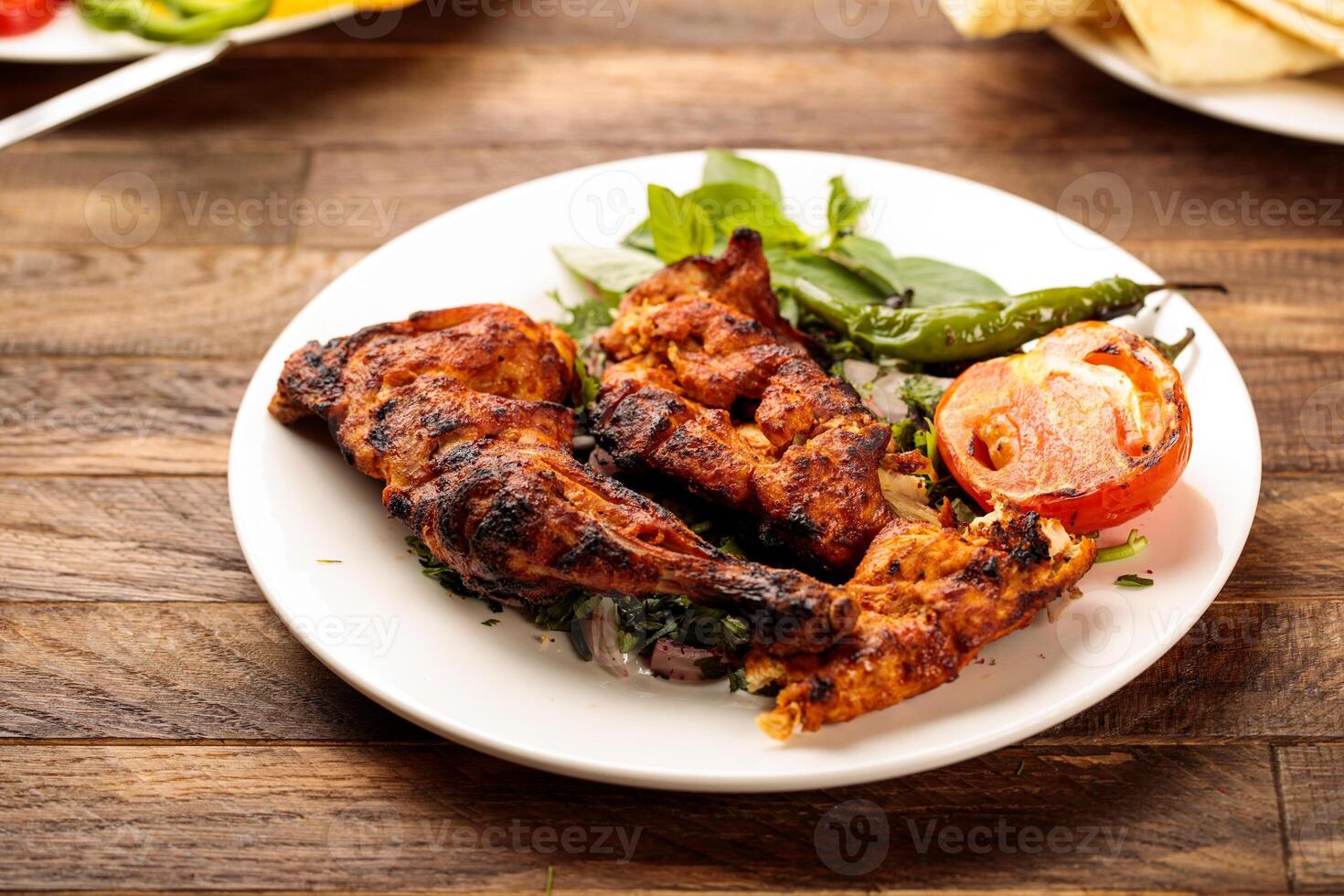 Grilled chicken with tomato and salad served in a dish isolated on wooden table background side view of fastfood photo