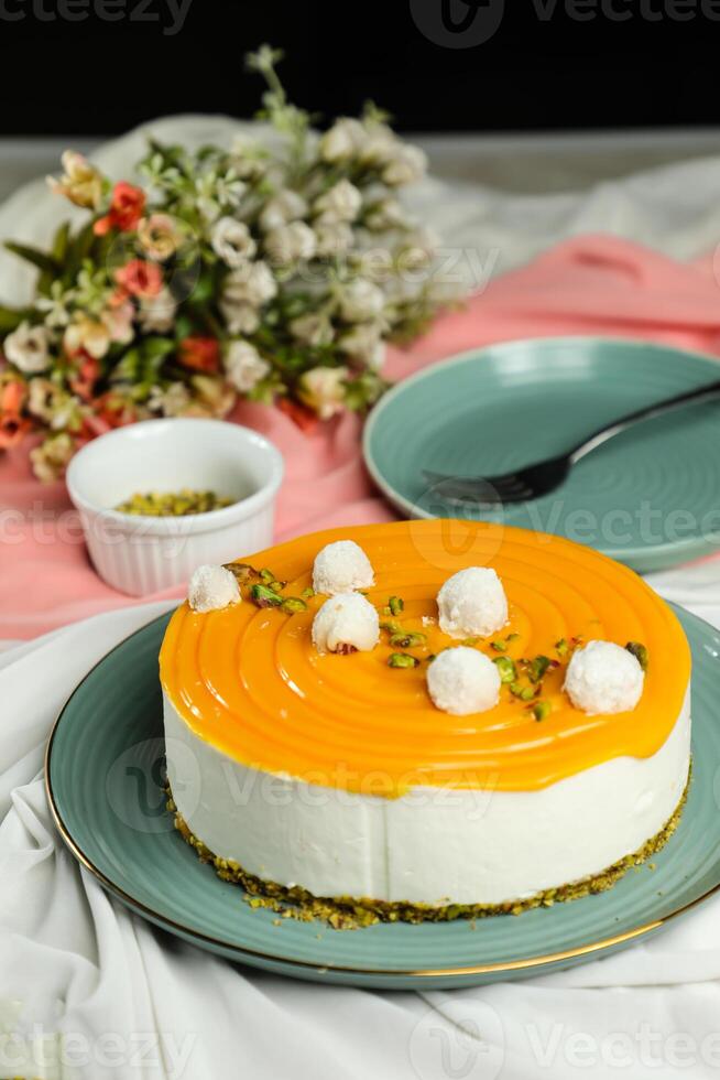 Mango Yogurt Cake topping with pistachio fork and flowers served in plate isolated on napkin side view cafe bake food photo