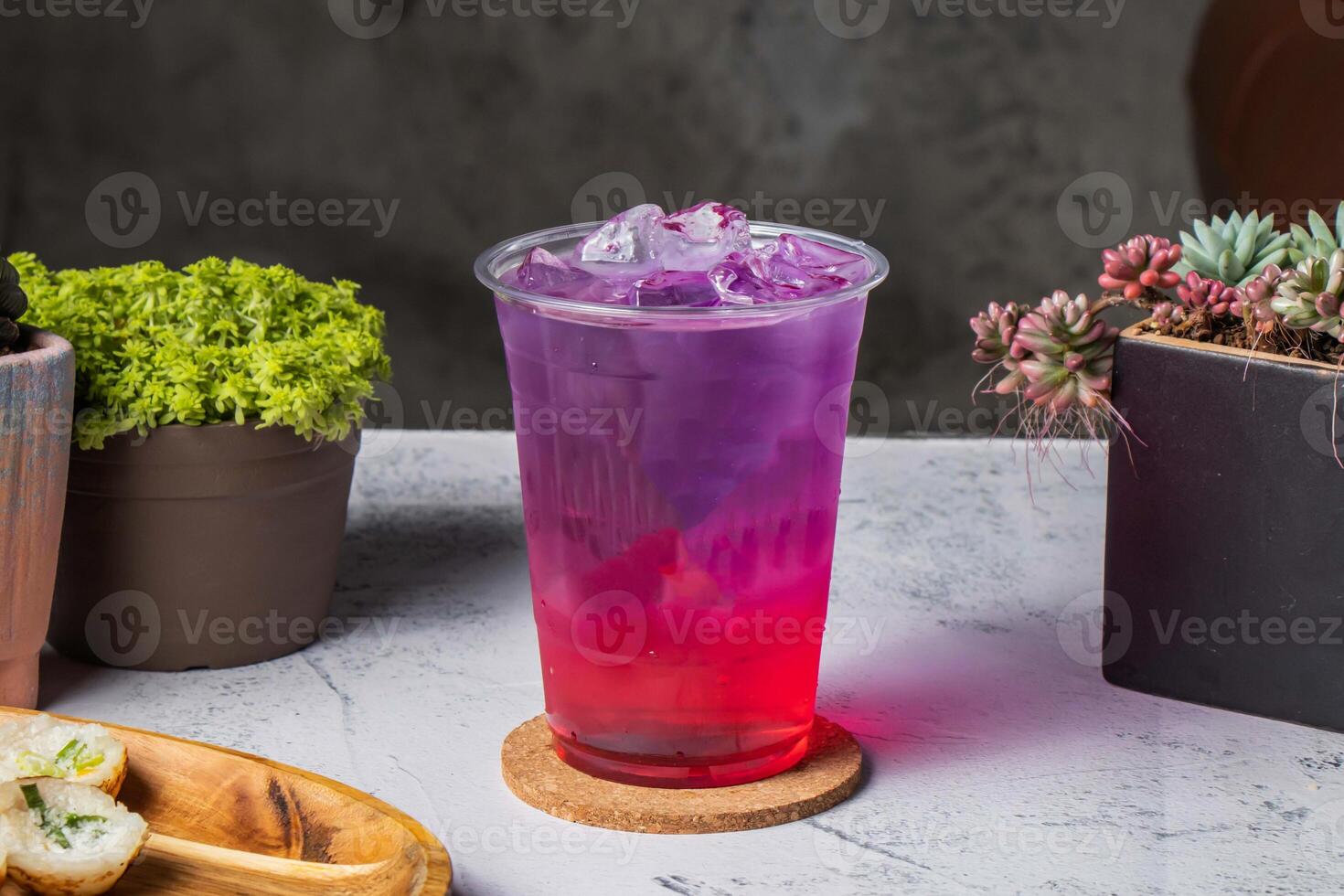 Berry Bubbles and cocktail colorful tea served in disposable glass with ice cube isolated on wooden board side view of taiwanese ice drink photo