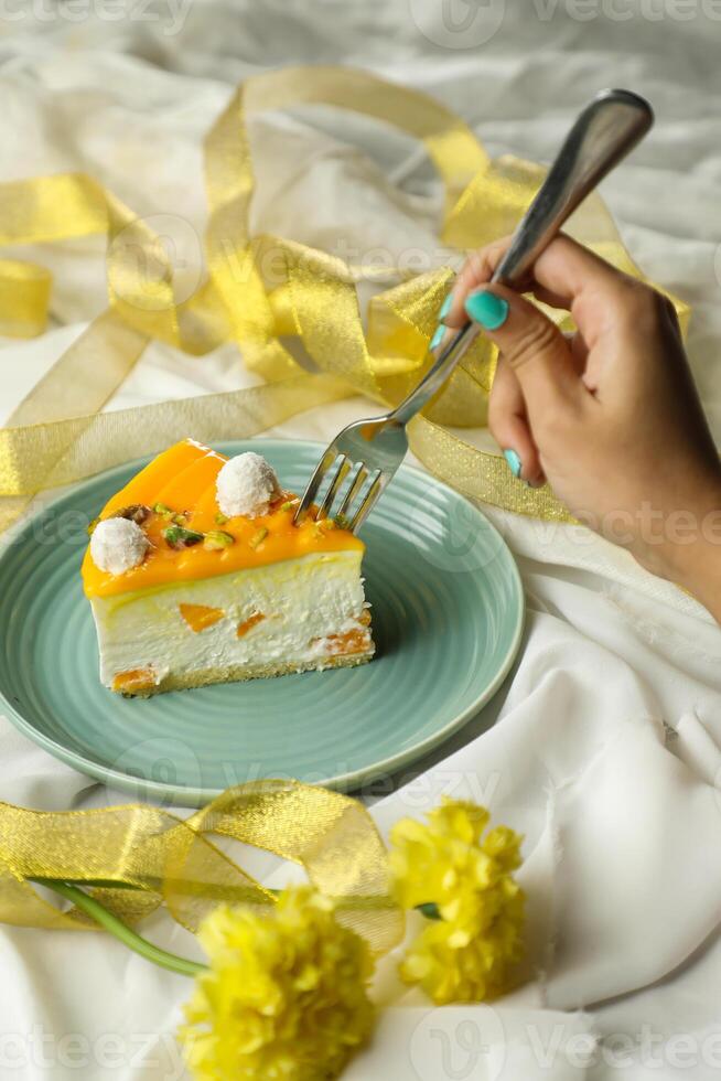 Mango Yogurt Cake slice topping with pistachio fork and flowers served in plate isolated on napkin side view cafe bake food photo