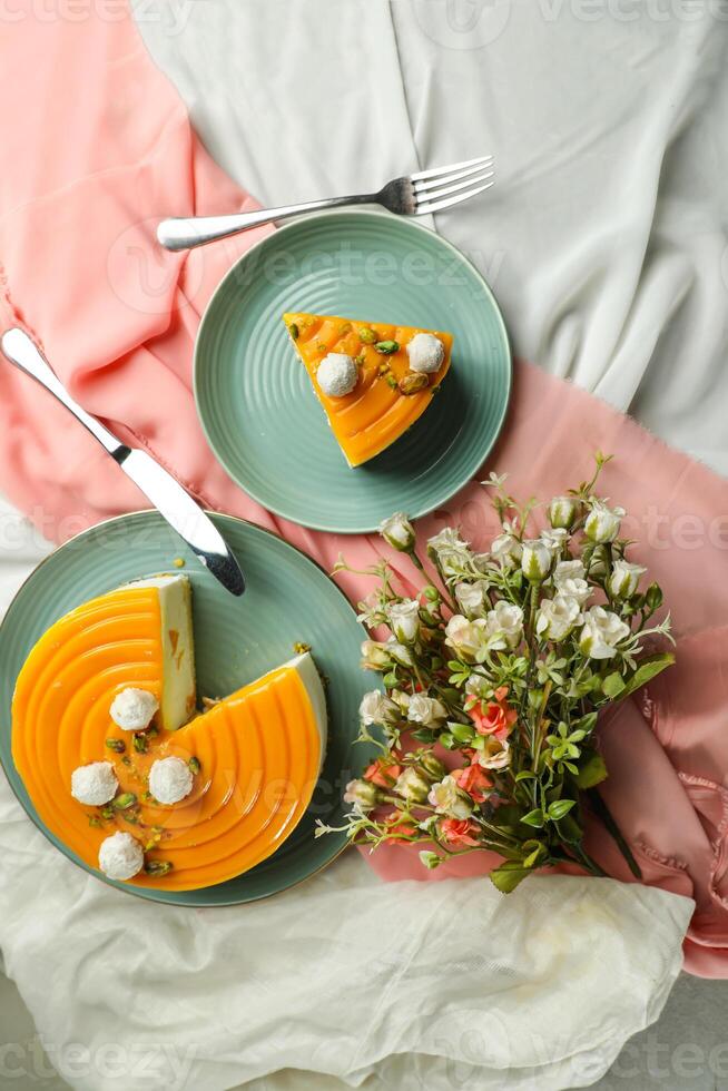 Mango Yogurt Cake slice topping with pistachio fork and flowers served in plate isolated on napkin top view cafe bake food photo