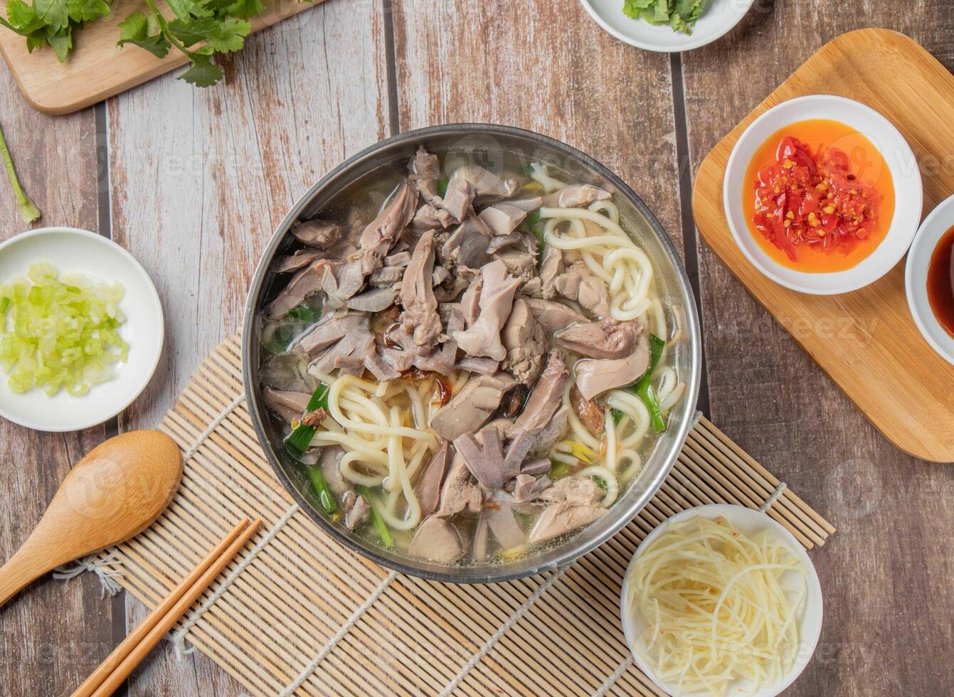 Pork meat Noodle soup with chilli sauce, noodles, spoon and chopsticks served in dish isolated on napkin top view of hong kong food photo
