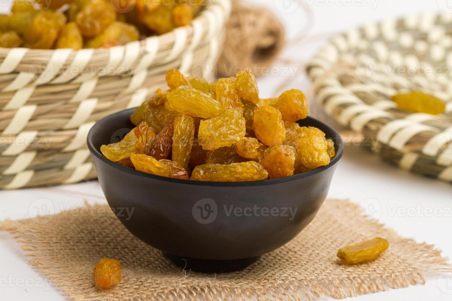 Dried grapes yellow small served in bowl isolated on napkin side view of dry fruits on grey background photo