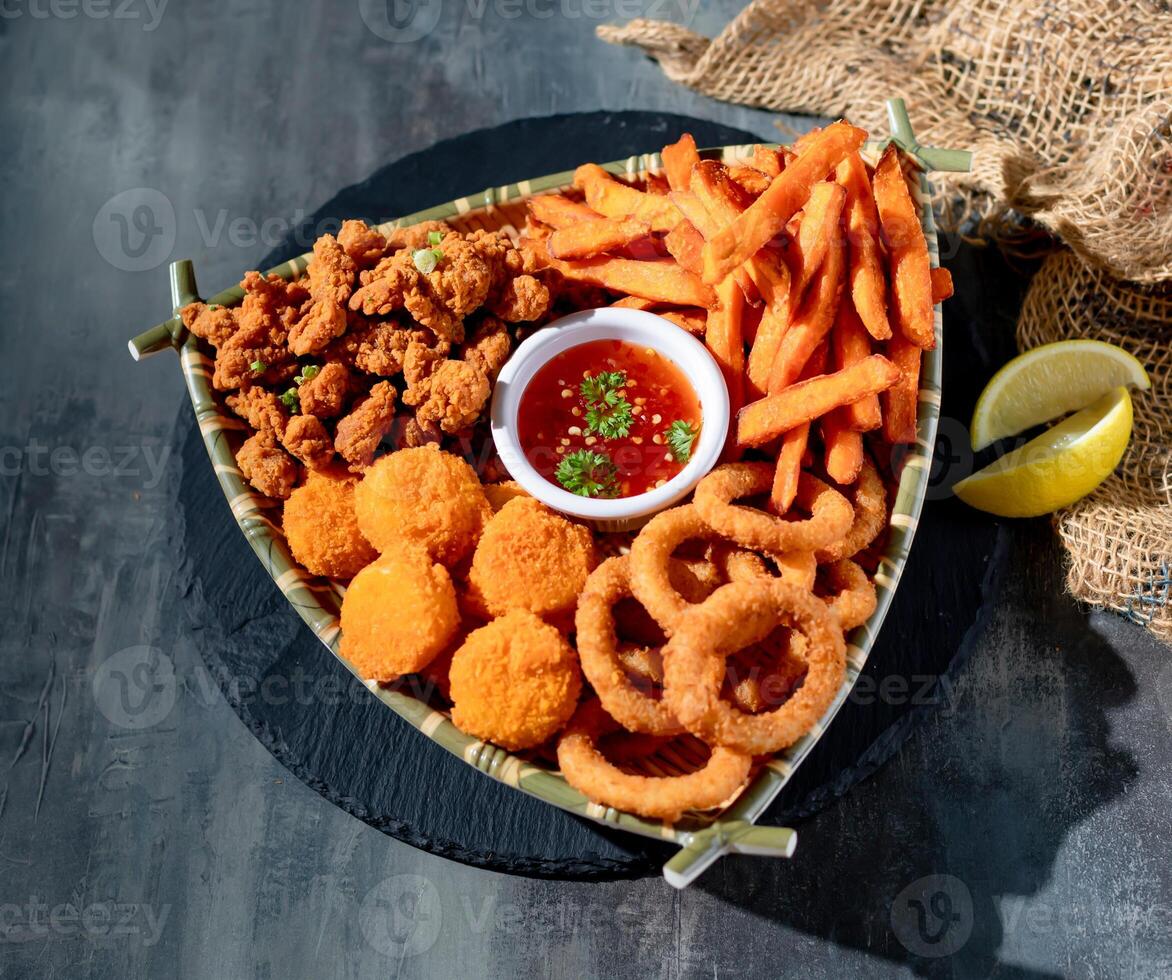 Snacker Platter with onion ring, french fries, Golden Scallops, chili sauce in a dish top view on dark background photo