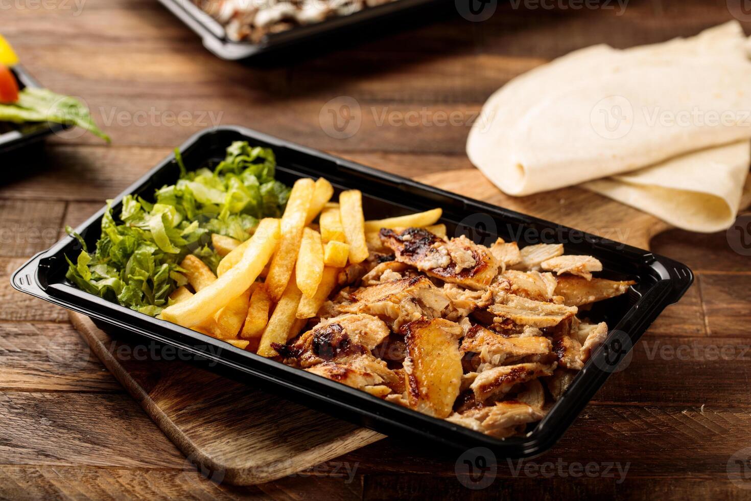 Chicken Shawarma plate with salad, fries and pita bread served in a dish isolated on wooden table background side view of fastfood photo