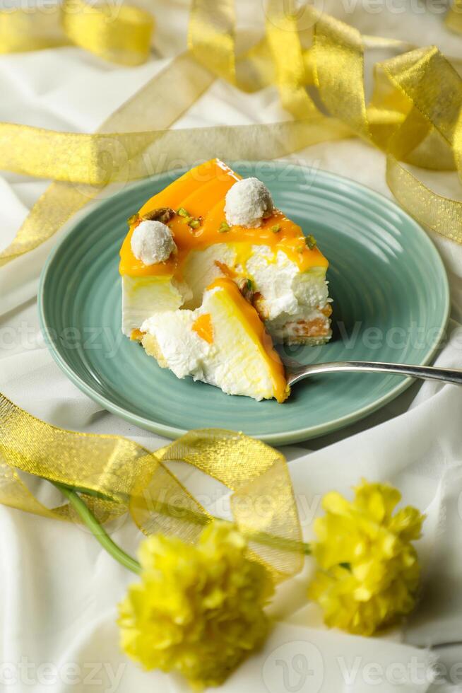 Mango Yogurt Cake slice topping with pistachio fork and flowers served in plate isolated on napkin side view cafe bake food photo