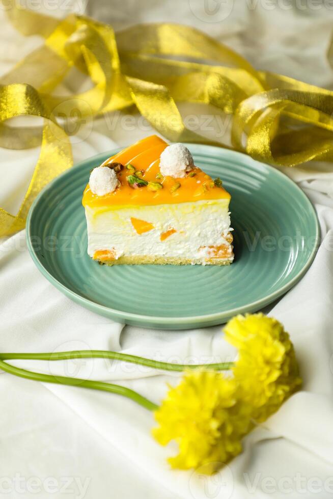 Mango Yogurt Cake slice topping with pistachio fork and flowers served in plate isolated on napkin side view cafe bake food photo