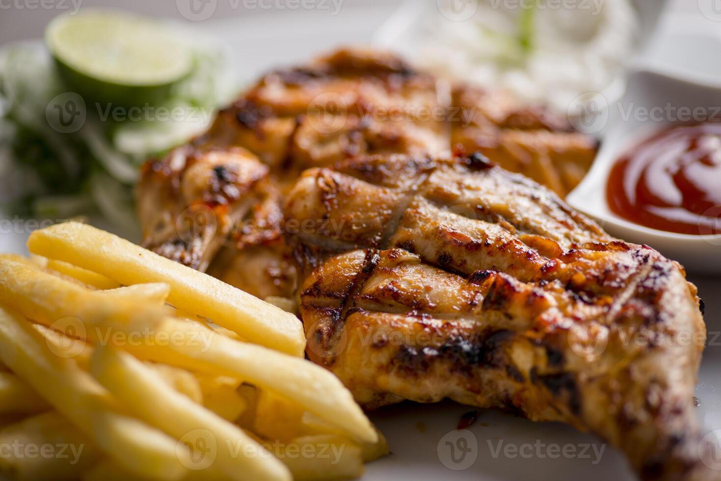 A la parrilla pollo con francés papas fritas servido en plato aislado en gris antecedentes parte superior ver de Arábica comida foto