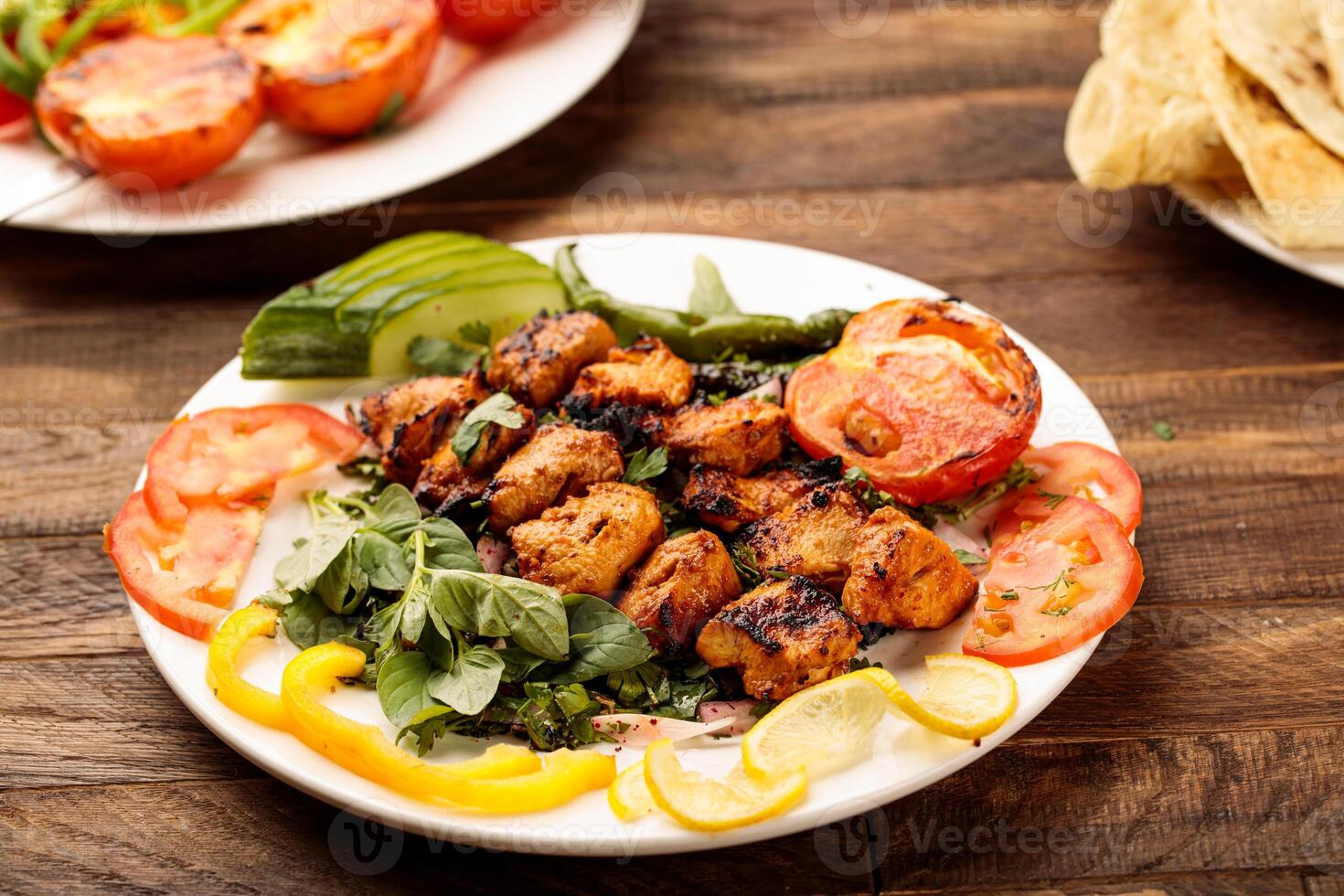 Chicken Grill Tikka boti kabab with tomato, salad and bread served in a dish isolated on wooden table background side view of fastfood photo