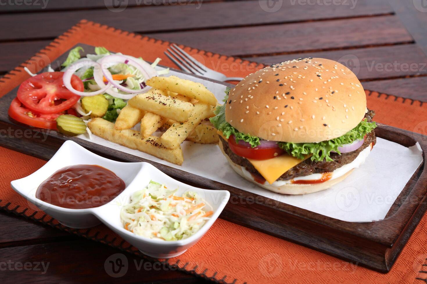A la parrilla angus carne de vaca hamburguesa con papas fritas, ensalada y tomate salsa servido en un plato aislado en mesa lado ver de medio este comida foto