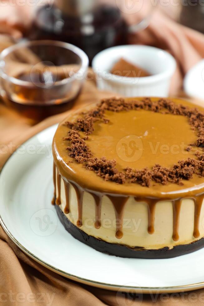 Salted Caramel Blondie cake include chocolate cream, sugar with fork, cup of coffee and pot served on board isolated on napkin side view of cafe food photo