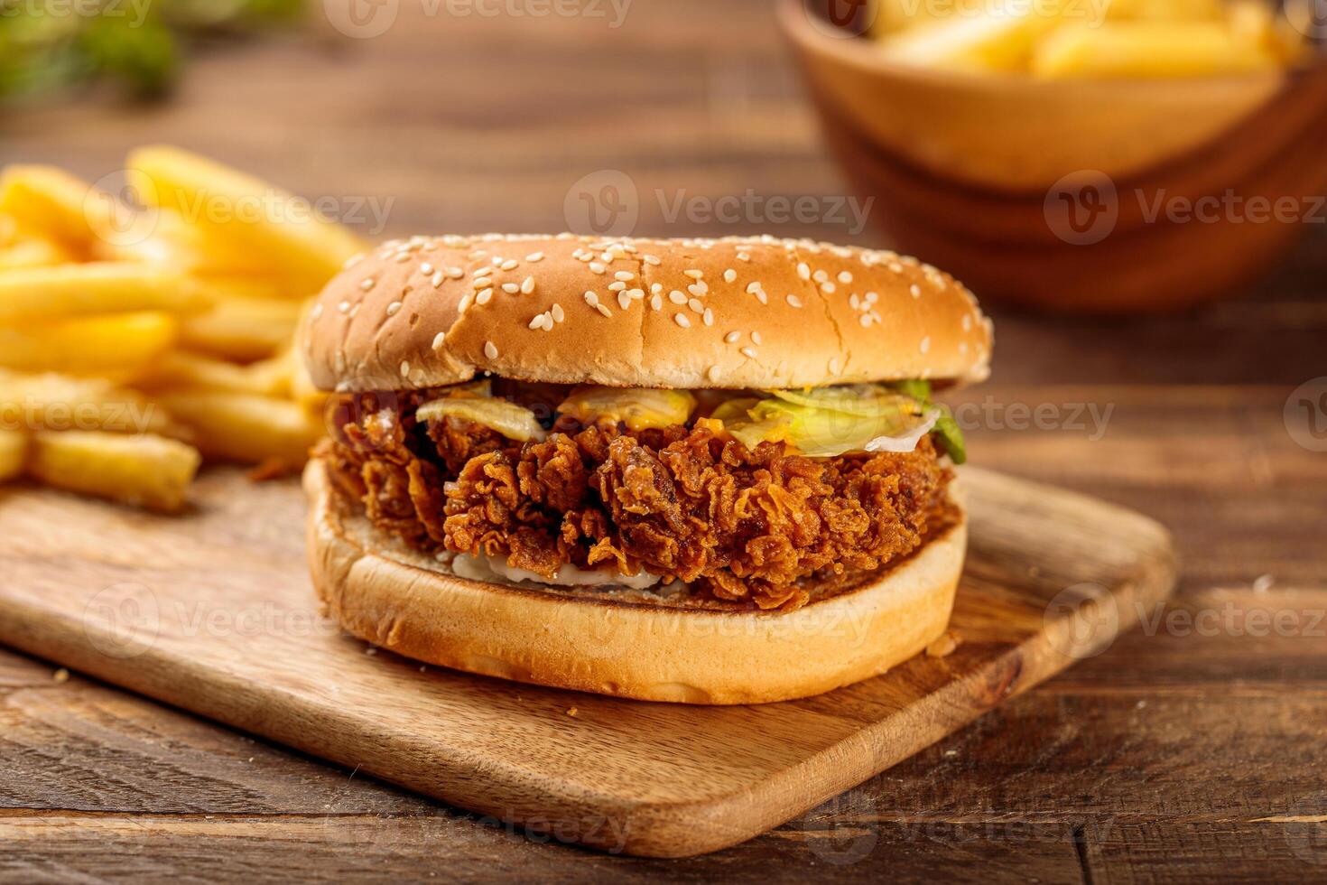 Chicken zinger burger with french fries served in a cutting board isolated on wooden table background side view of fastfood photo