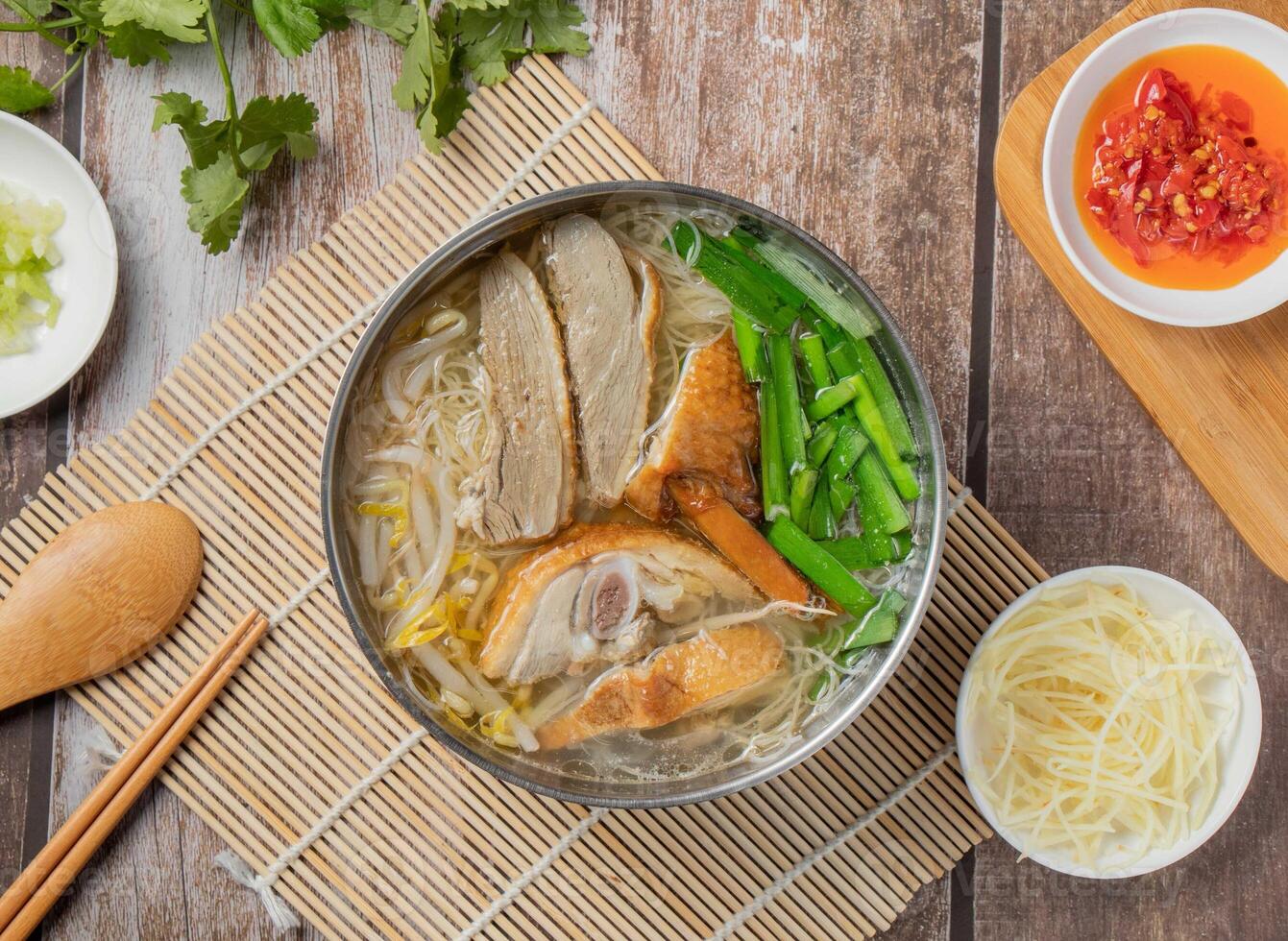 Duck meat rice noodles with chilli sauce, noodles, spoon and chopsticks served in dish isolated on napkin top view of hong kong food photo