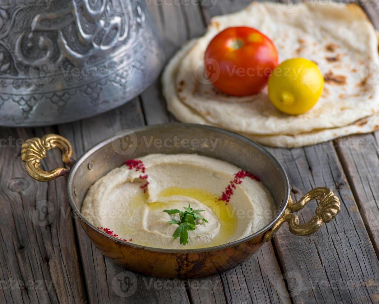 Hommous with pita served in dish side view on wooden table background photo