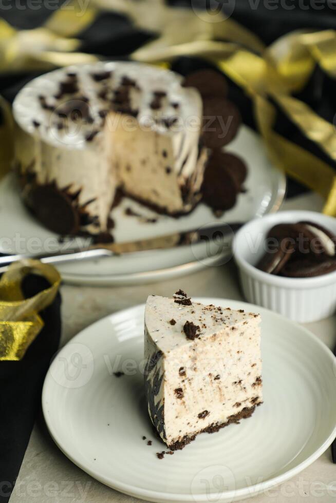 Oreo Cheesecake slice include chocolate, cream, sugar with fork and flowers served in plate isolated on napkin side view of cafe food photo