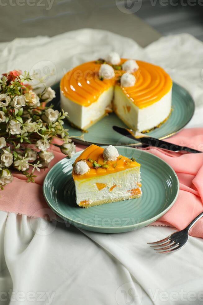 Mango Yogurt Cake slice topping with pistachio fork and flowers served in plate isolated on napkin side view cafe bake food photo