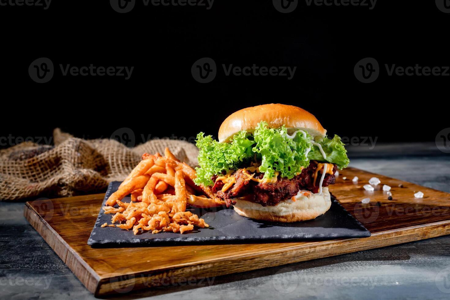 beef burgers with tomato, cheese, ketchup and french fries in a black dish top view on dark background photo