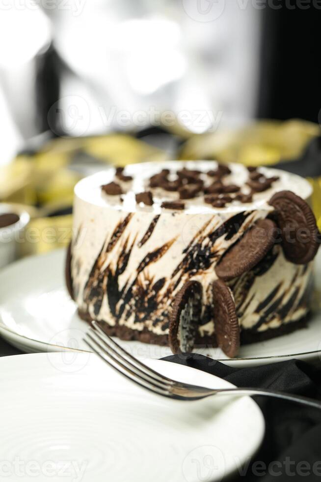 Oreo Cheesecake include chocolate, cream, sugar with fork and flowers served in plate isolated on napkin side view of cafe food photo