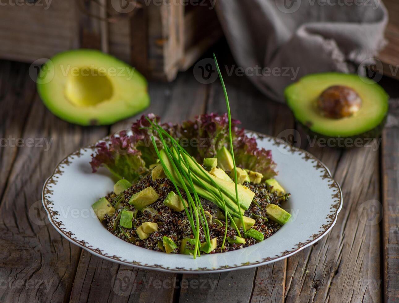 Healthy avocado quinoa salad served in a dish isolated on wooden background side view photo