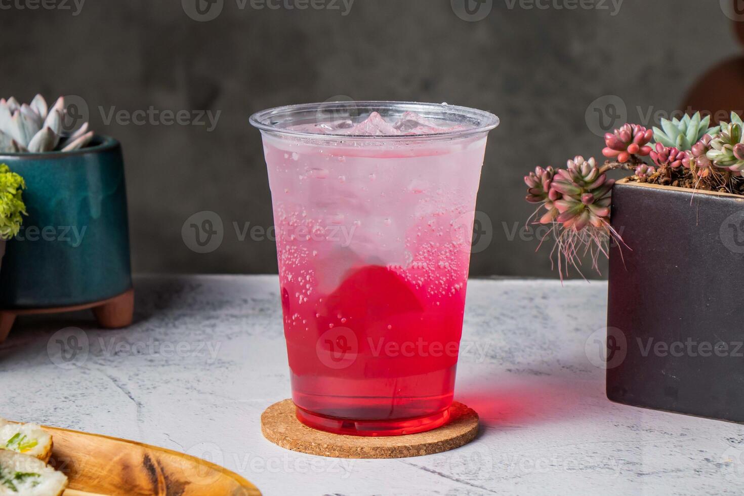 Berry Bubbles tea served in disposable glass with ice cube isolated on wooden board side view of taiwanese ice drink photo