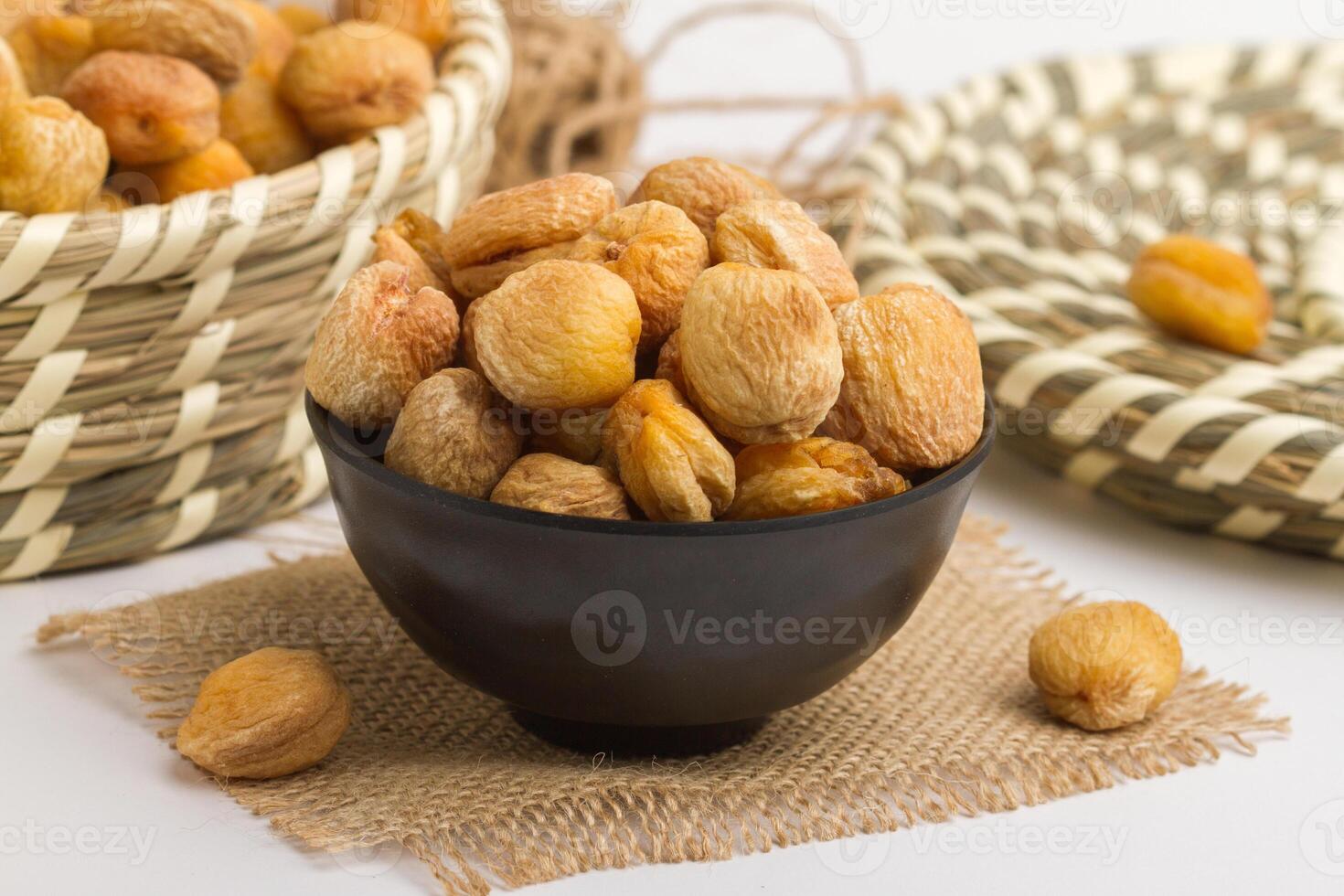 Dry apricot served in bowl isolated on napkin side view of dry fruits on grey background photo