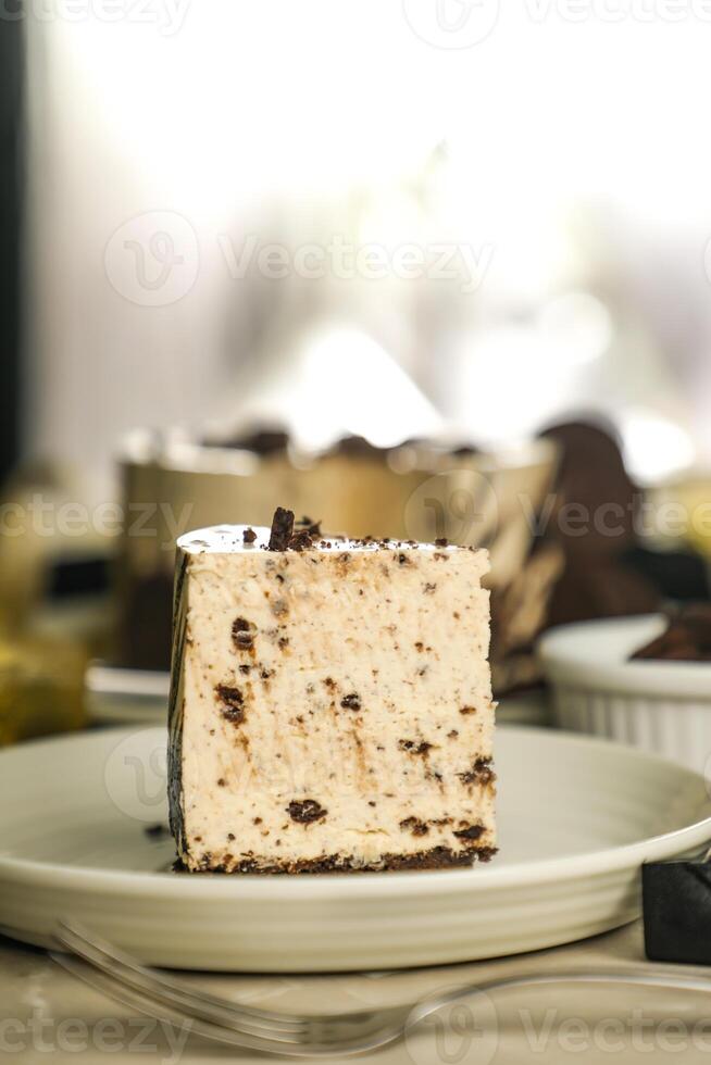 Oreo Cheesecake slice include chocolate, cream, sugar with fork and flowers served in plate isolated on napkin side view of cafe food photo