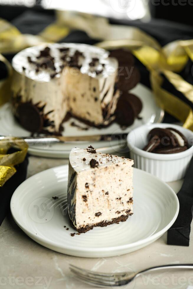 Oreo Cheesecake slice include chocolate, cream, sugar with fork and flowers served in plate isolated on napkin side view of cafe food photo