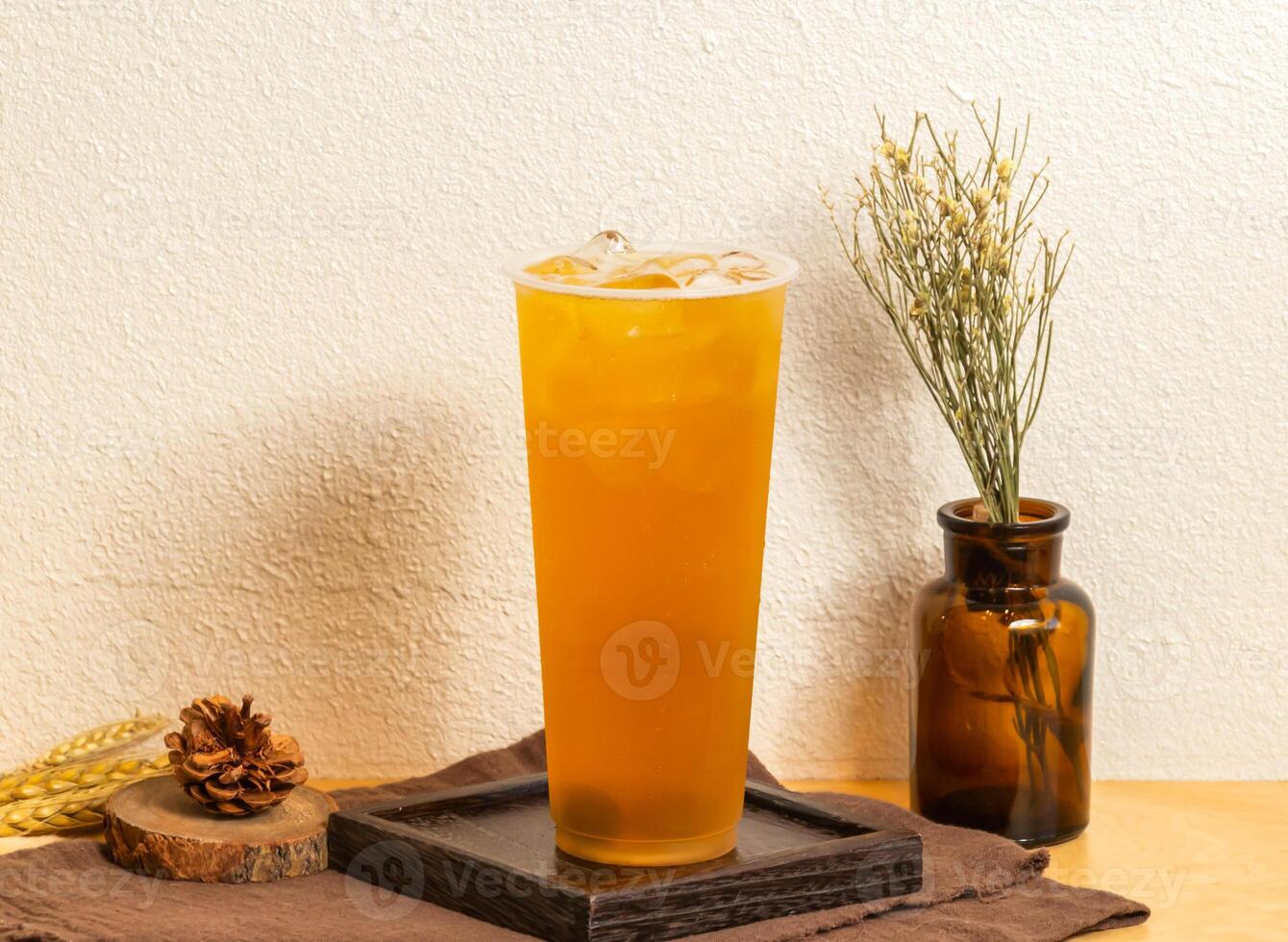 Iced Rich plum green tea served in disposable glass isolated on wooden board side view of taiwanese ice drink photo