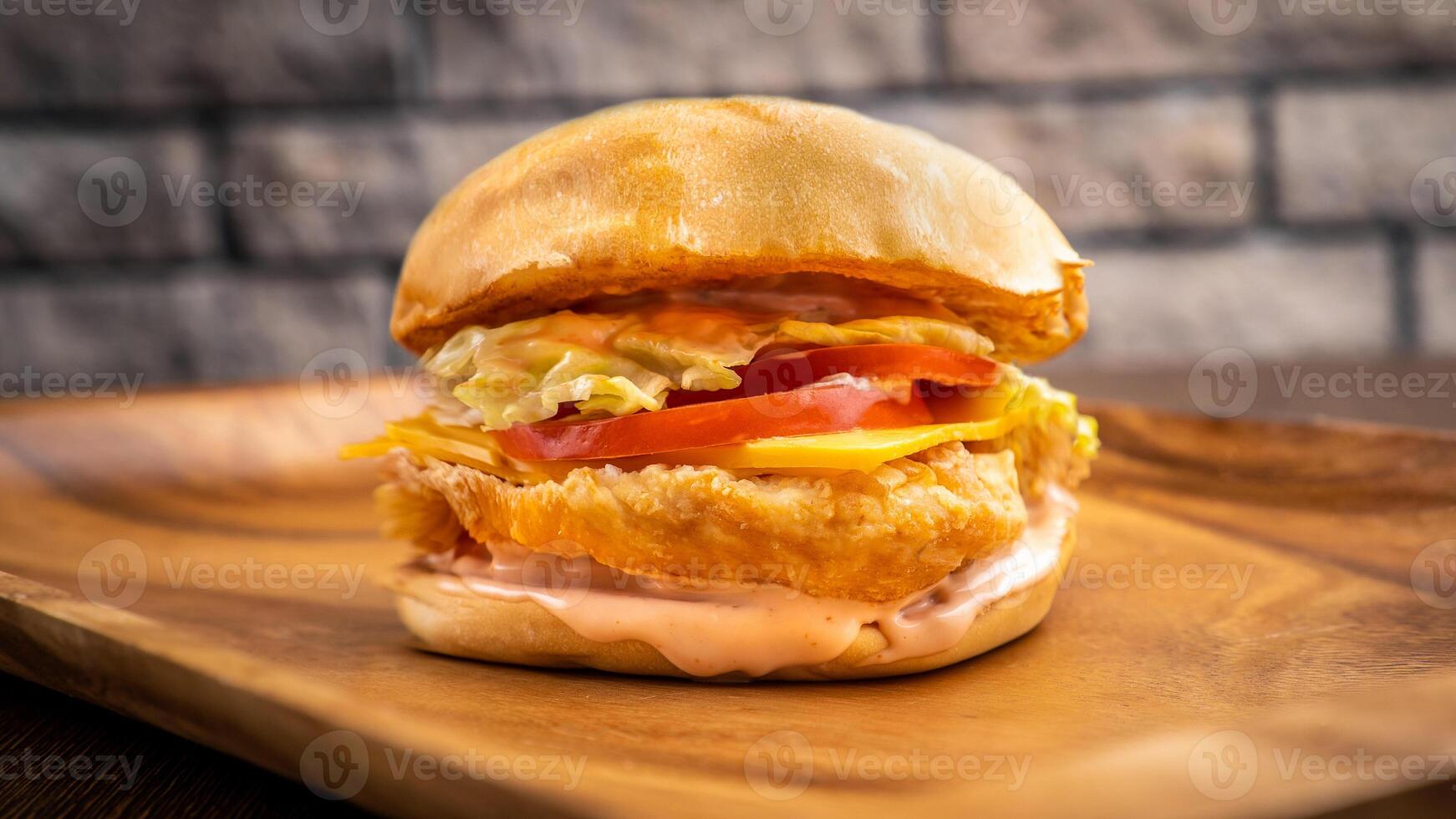 Crispy chicken burger isolated on wooden board side view on table fast food photo