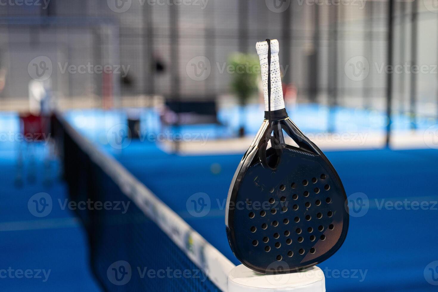 Paddle tennis. Padel racket and ball in front of an outdoor court. photo